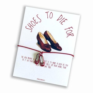 May include: Red ruby slipper charm bracelet with the text "Shoes to Die For" and the text "The idea behind a wish bracelet is to make a wish as you tie it on your wrist. When it falls off from wear, your wish will come true."
