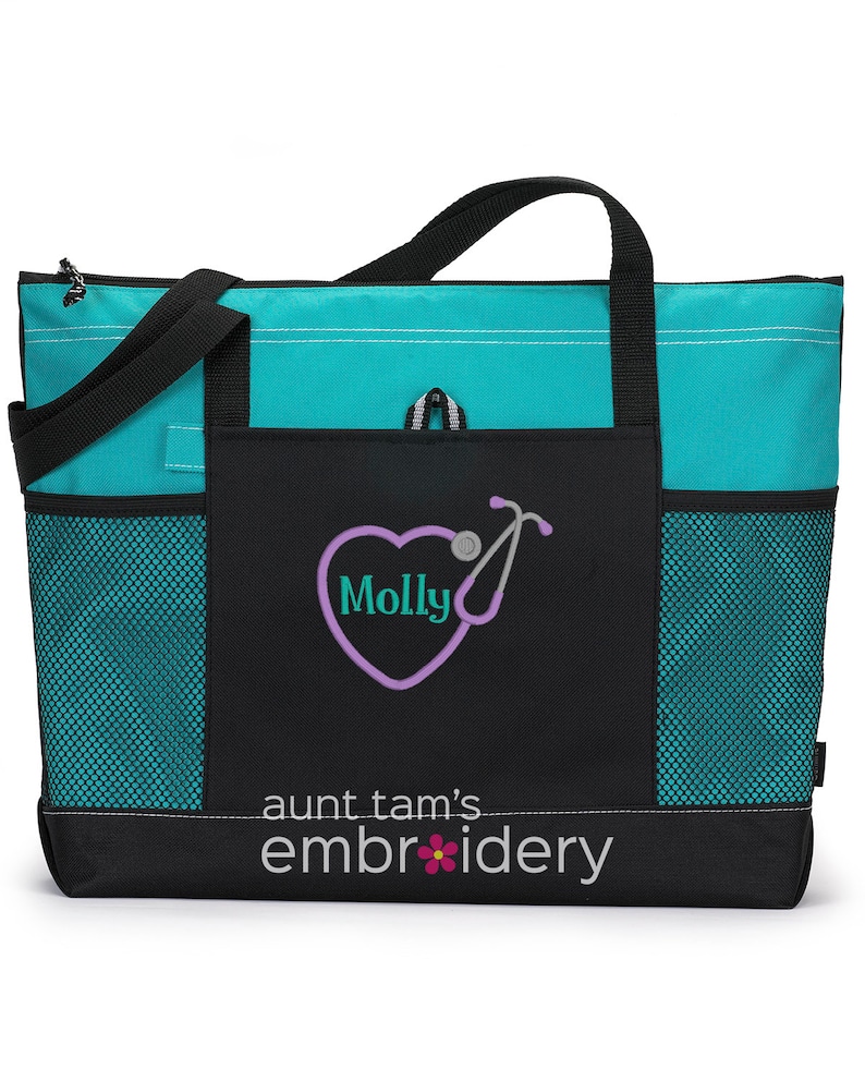 Puede incluir: Un bolso tote turquesa y negro con asas y bolsillos laterales negros. La parte delantera presenta un dise&ntilde;o de estetoscopio en forma de coraz&oacute;n con el nombre "Molly" y el texto "aunt tam's embroidery". La bolsa est&aacute; dise&ntilde;ada para transportar art&iacute;culos.