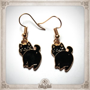 May include: Gold cat earrings with black enamel. The cats are sitting with their tails curled around their legs.