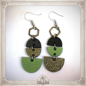 May include: A pair of dangle earrings featuring three geometric shapes. The top shape is a hexagon, the middle shape is a half circle, and the bottom shape is a full circle. The earrings are made of black, green, and gold glitter.