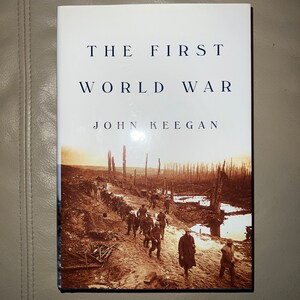 May include: A book titled "The First World War" by John Keegan. The cover features a black and white photograph of soldiers walking through a trench.