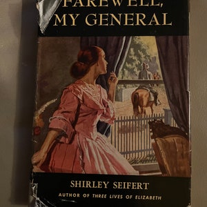 May include: A vintage book cover with the title "Farewell, My General" by Shirley Seifert, author of "Three Lives of Elizabeth". The cover features a woman in a pink dress looking out a window at a man on horseback.