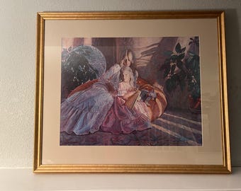May include: A framed print of a painting depicting two women sitting on a couch. The woman in the foreground is wearing a purple dress and holding a book. The woman in the background is wearing a white dress and has her arm around the woman in the foreground. The painting is set in a room with a plant in the background.