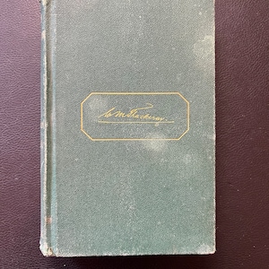 May include: A green hardcover book with gold lettering on the spine and front cover. The front cover has a gold border around the title "Wm Thackeray".