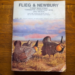 May include: A vintage Flieg & Newbury catalog from Torrington, Connecticut, featuring an illustration of prairie chickens in a grassy field under a sunset sky. The cover includes business contact details and a list of sporting goods categories.