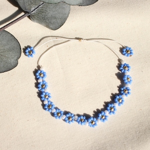 Può includere: Un braccialetto delicato in perle blu e bianche con un design floreale. Il braccialetto è realizzato con piccole perle rotonde e ha una semplice chiusura regolabile.