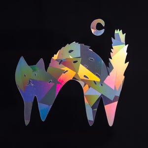 Könnte beinhalten: Eine farbenfrohe, schillernde Katzensilhouette mit einem Halbmond darüber. Die Katze besteht aus einem holografischen Material, das Licht in einem Regenbogen von Farben reflektiert.