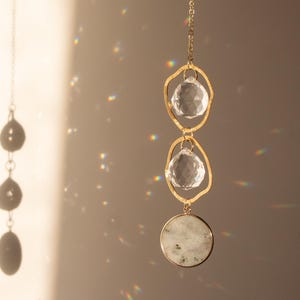 Könnte beinhalten: Eine goldene Kette mit drei Kristallanhängern, die daran hängen. Die Kristalle sind klar und facettiert, und die Kette ist zart. Die Kristalle sind in goldenen Ringen aufgehängt.