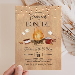 Puede incluir: Una invitaci&oacute;n r&uacute;stica para una fogata en el patio trasero, con una ilustraci&oacute;n en acuarela de una fogata, malvaviscos y una taza. El texto dice "Backyard Bonfire" y anuncia el d&eacute;cimo cumplea&ntilde;os de Jackson el 18 de octubre a las 2:00 PM.