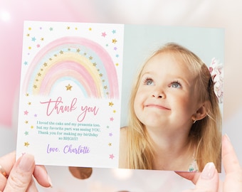 Puede incluir: Un arcoíris rosa y azul con estrellas doradas brillantes sobre un fondo blanco. El texto "gracias" está escrito en una fuente dorada. El texto "Me encantó el pastel y mis regalos también, pero mi parte favorita fue verte a TI. Gracias por hacer mi cumpleaños tan BRILLANTE! Con amor, Charlotte" está escrito en negro. Una foto de una niña con cabello rubio está en el lado derecho de la tarjeta.
