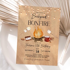 Puede incluir: Una invitaci&oacute;n r&uacute;stica para una fiesta de cumplea&ntilde;os con fogata en el patio trasero. El dise&ntilde;o presenta una ilustraci&oacute;n de fogata con malvaviscos, s'mores y una taza. El texto dice "Backyard Bonfire" y "10&ordm; Cumplea&ntilde;os de Jackson" con detalles del evento.