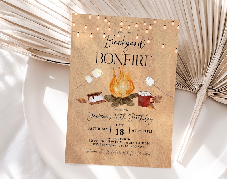 Puede incluir: Una invitaci&oacute;n r&uacute;stica para una fiesta de cumplea&ntilde;os con fogata en el patio trasero. El dise&ntilde;o presenta una ilustraci&oacute;n de fogata con malvaviscos, s'mores y una taza. El texto dice "Backyard Bonfire" y "10&ordm; Cumplea&ntilde;os de Jackson" con detalles del evento.