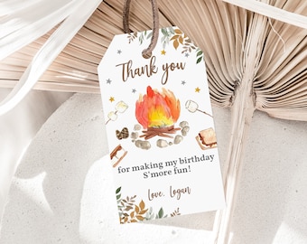 May include: A white thank you tag with a campfire illustration. The campfire is orange and red with a few logs and rocks. There are marshmallows on sticks and a s'more on the side. The text reads "Thank you for making my birthday s'more fun! Love, Logan".