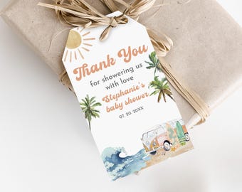 May include: A gift tag with a beach theme, featuring a watercolor illustration of a vintage van, surfboards, and palm trees. The tag says "Thank You" and mentions a baby shower. The tag is tied to a wrapped gift with raffia.