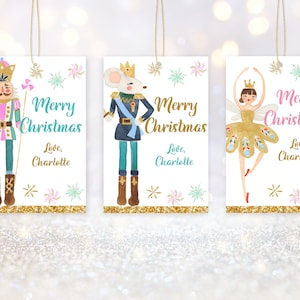 May include: Three Christmas gift tags featuring illustrations of a nutcracker, a mouse, and a ballerina. Each tag has a white background with gold glitter accents and the text "Merry Christmas" and "Love, Charlotte".
