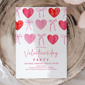 Puede incluir: Una invitaci&oacute;n a una fiesta de San Valent&iacute;n con corazones y lazos de acuarela rosas y rojos. El texto de la invitaci&oacute;n dice "Join us for a Valentine's Day Party" con detalles del evento. La invitaci&oacute;n est&aacute; sobre un fondo blanco.