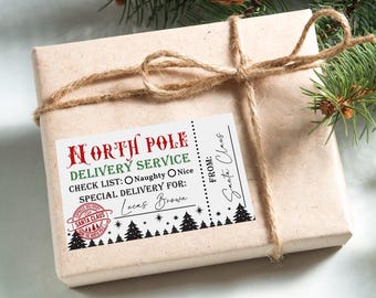 Peut inclure: Une étiquette cadeau blanche avec du texte rouge et vert qui dit "North Pole Delivery Service". L'étiquette a une liste de contrôle avec les options "Naughty" et "Nice" et un espace pour un nom de livraison spécial. L'étiquette a également un tampon rouge et noir qui dit "Express Delivery Santa Claus". L'étiquette est attachée à une boîte cadeau brune avec de la ficelle.