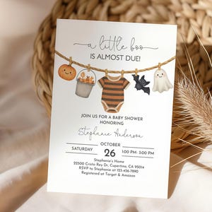 May include: A baby shower invitation with a Halloween theme. The invitation features a clothesline with a pumpkin, a bucket, a onesie, a bat, and a ghost. The text reads "a little boo is almost due!" and includes event details.