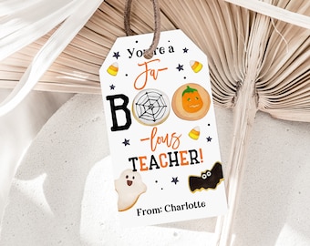 Può includere: Etichetta regalo bianca con testo nero che recita "You're a fa-BOO-lous TEACHER!" con illustrazioni di biscotti a forma di ragnatela, zucca, fantasma e pipistrello. L'etichetta riporta anche "From: Charlotte".