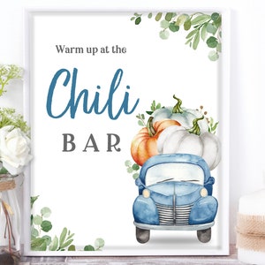 May include: A white sign with blue text that reads "Warm up at the Chili BAR". A blue pickup truck with pumpkins in the bed is illustrated on the sign. The sign is decorated with green leaves.