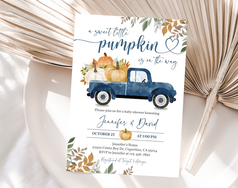 Pu&ograve; includere: Un camioncino blu con una cassone pieno di zucche e foglie autunnali. Il camioncino &egrave; su uno sfondo bianco con il testo "a sweet little pumpkin is on the way".