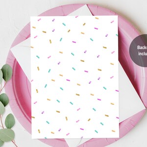May include: A white card with a repeating pattern of gold, pink, and blue sprinkles. The back of the card is included.