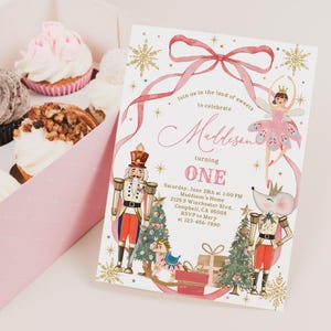 May include: A pink invitation with a watercolor illustration of a ballerina, nutcrackers, and a mouse, with the text "Maddison turning ONE". Cupcakes in a pink box are in the background.