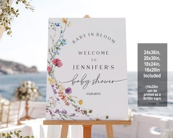 Può includere: Un cartello di benvenuto bianco con un design floreale ad acquerello che presenta una ghirlanda di fiori colorati. Il testo recita "Baby in Bloom, Welcome to Jennifer's Baby Shower, 03.20.20XX". Il cartello è disponibile in diverse dimensioni: 24x36 pollici, 20x30 pollici, 18x24 pollici e 16x20 pollici. La dimensione 16x20 pollici può essere stampata come un cartello 8x10 pollici.