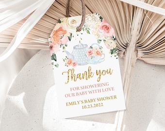 May include: A white thank you tag with gold glitter text that says "Thank you" and "For showering our baby with love". The tag also includes the text "Emily's Baby Shower 10.23.2022" and a watercolor illustration of a teapot and teacup with floral accents.