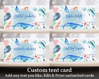 May include: Four printable tent cards with an ocean theme. Each card features a different ocean animal and a different food item. The cards say "Starfish Sandwiches", "Dolphin Delight", "Mermaid's Macarons", and "Coral Reef Cupcakes".
