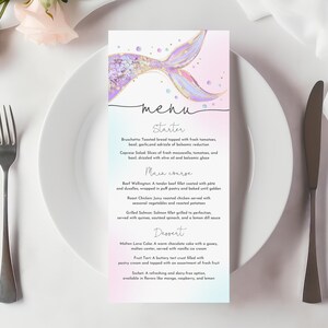 Op de afbeelding: Een menukaart met zeemeerminthema met een pastelkleurige achtergrond, met een illustratie van een zeemeerminstaart. Het menu bevat voorgerechten, hoofdgerechten en desserts. Een vork, mes en bord zijn ook zichtbaar.