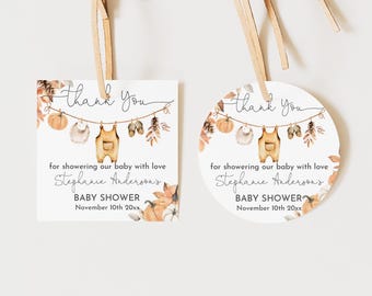 May include: Two baby shower gift tags, one square and one round, with a watercolor design. The tags feature the text "Thank You" and "Baby Shower" with a clothesline of baby items. The tags are tied with a beige ribbon.