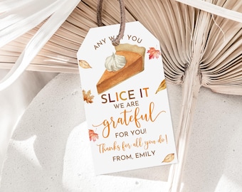 May include: A white tag with a brown string attached. The tag has a watercolor illustration of a slice of pumpkin pie with a whipped cream topping. The text on the tag reads "Any We You Slice It We Are Grateful For You! Thanks for all you do! From, Emily."