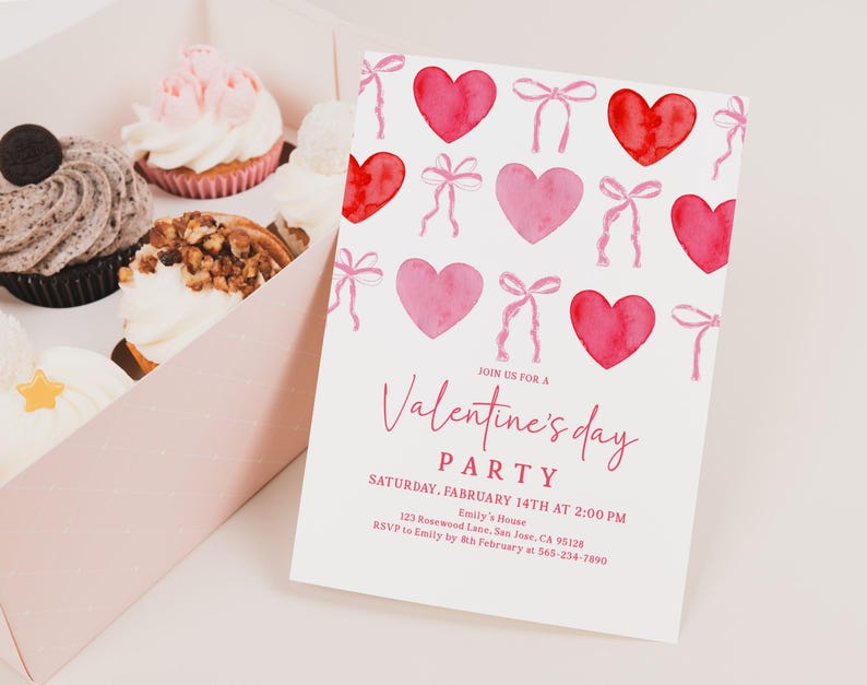 Puede incluir: Una invitaci&oacute;n a una fiesta de San Valent&iacute;n con corazones y lazos de acuarela. La invitaci&oacute;n est&aacute; sobre un fondo blanco e incluye los detalles de la fiesta. Una caja de cupcakes con varios ingredientes est&aacute; en el fondo.