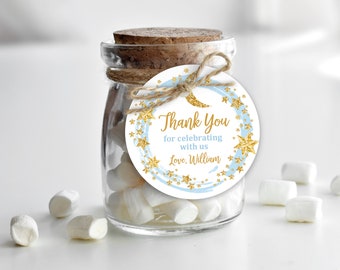 Può includere: Un piccolo barattolo di vetro pieno di marshmallow bianchi con un'etichetta di ringraziamento blu e dorata a forma di stella e mezzaluna. L'etichetta recita "Grazie per aver festeggiato con noi Amore, William".