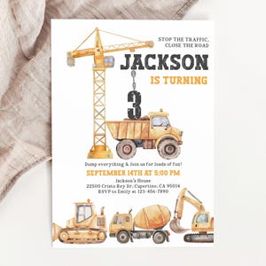 May include: A watercolor-style birthday invitation featuring construction vehicles. The design includes a crane, dump truck, and other equipment. The text reads "JACKSON IS TURNING 3" and includes party details. The invitation is on a white background.