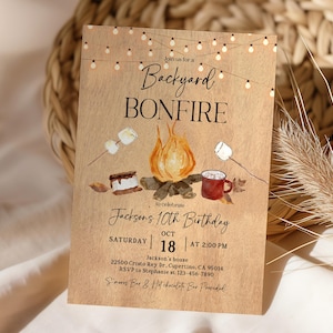 Op de afbeelding: Een rustieke uitnodiging voor een kampvuur in de achtertuin, met aquarel illustraties van een kampvuur, marshmallows, s'mores en een mok. De tekst luidt "Backyard Bonfire" en kondigt een 10e verjaardag aan op 18 oktober.