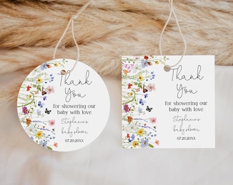 May include: Two white baby shower favor tags with floral and butterfly designs. One tag is round, the other square. Both tags have the text "Thank You" and "for showering our baby with love". The tags are tied with twine.