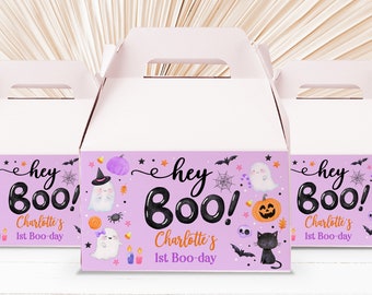 Op de afbeelding: Paarse en witte cadeaudoosjes met een Halloween-thema. De doosjes hebben een spook-, pompoen- en vleermuisontwerp met de tekst "Hey Boo! Charlotte's 1st Boo-day".