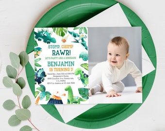 May include: A dinosaur-themed first birthday party invitation featuring a watercolour illustration of dinosaurs, plants, and a volcano. The invitation includes the text "STOMP, CHOMP RAW! LET'S PARTY LIKE A DINOSAUR BENJAMIN IS TURNING 1!" and details for the party, such as the date, time, location, and RSVP information.