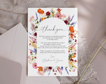 May include: A thank you card with a watercolor floral wreath border in shades of pink, orange, red, yellow, and purple. The text reads "thank you" and includes a message expressing gratitude for gifts and well wishes at a baby shower. The card is signed "Love, Stephanie & James".