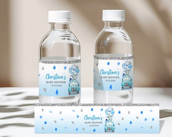 Könnte beinhalten: Zwei durchsichtige Wasserflaschen mit blauen und silbernen Etiketten. Die Etiketten zeigen einen blauen LKW mit einem Baby-Elefanten und Ballons. Der Text auf den Etiketten lautet "Christina's Baby Shower 10.30.20XX".