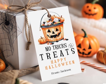 Może przedstawiać: Etykieta prezentu na Halloween z ilustracją wiadra z dyni wypełnionego słodyczami i dyniami. Na etykiecie widnieje napis "No Tricks Just Treats Happy Halloween" i "From: Jackson". Etykieta jest przymocowana do białego pudełka prezentowego sznurkiem.