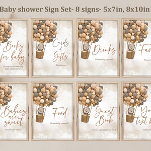 Op de afbeelding: Set van acht printbare babyborrelborden met een thema van een luchtballon met een schattige beer in een mand. De borden bevatten tekst zoals "Boeken voor baby", "Kaarten & Cadeaus", "Drankjes", "Favorieten", "Baby's zijn zoet", "Eten", "Gastenboek" en "Uw tekst hier".