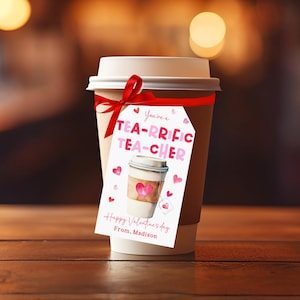 May include: A coffee cup with a white lid and a red ribbon tied around it. A tag with the words "You're a TEA-RRIFIC TEACHER" and "Happy Valentine's Day From. Madison" is attached to the cup. Pink hearts are scattered around the tag.
