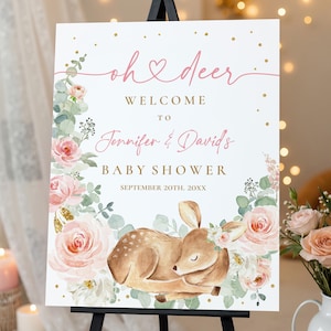 Peut inclure: Panneau de bienvenue pour une baby shower avec le texte "oh deer" et "Bienvenue à Jennifer & David's Baby Shower". Le panneau présente une illustration à l'aquarelle d'un faon entouré de roses roses et de verdure, avec des accents dorés.