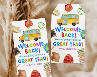 Puede incluir: Dos etiquetas de regalo rectangulares blancas con lazos de cinta marrón que presentan ilustraciones escolares en acuarela, incluyendo un autobús escolar amarillo, una manzana roja, un globo terráqueo, libros y una bolsa de almuerzo. El texto dice: Welcome Back! We are going to have a great year! Love, Charlotte.