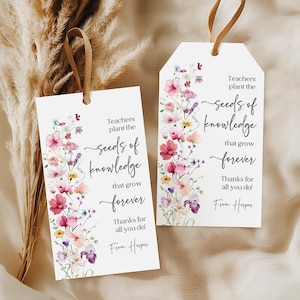 Könnte beinhalten: Zwei weiße Geschenkanhänger mit floralen Designs und brauner Schnur. Die Anhänger zeigen ein Aquarell-Blumenarrangement in Rosa, Lila und Gelb. Der Text auf den Anhängern lautet "Teachers plant the seeds of knowledge that grow forever."
