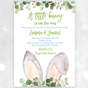 Op de afbeelding: Een uitnodiging voor een babyshower met een aquarel-illustratie van konijnenoren en groene bladeren. De tekst luidt "A little bunny is on the way. Please hop on over for a Baby Shower honoring Emma & James. Saturday, April 16th at 1:00 PM Emma's Home 1000 Eascalon Ave, Sunnyvale, CA, 94085 RSVP to Emma at 123-456-7890 Registered at Target and Amazon"