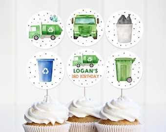 May include: Set of 6 green and white round cupcake toppers with a recycling theme. The toppers feature a green garbage truck, a green recycling bin, a blue recycling bin, and a white trash can with black garbage bags. The text "Logan's 3rd Birthday" is on one of the toppers.